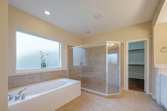 bathroom featuring tile patterned floors, vanity, plus walk in shower, and a textured ceiling