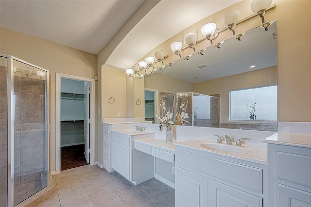 bathroom with tile patterned floors, a shower with door, vanity, and a textured ceiling