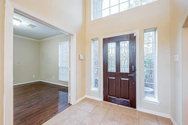 foyer entrance with a textured ceiling, plenty of natural light, light hardwood / wood-style floors, and crown molding