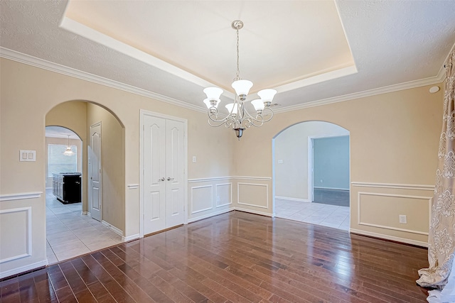 spare room with a chandelier, wood-type flooring, a textured ceiling, and ornamental molding