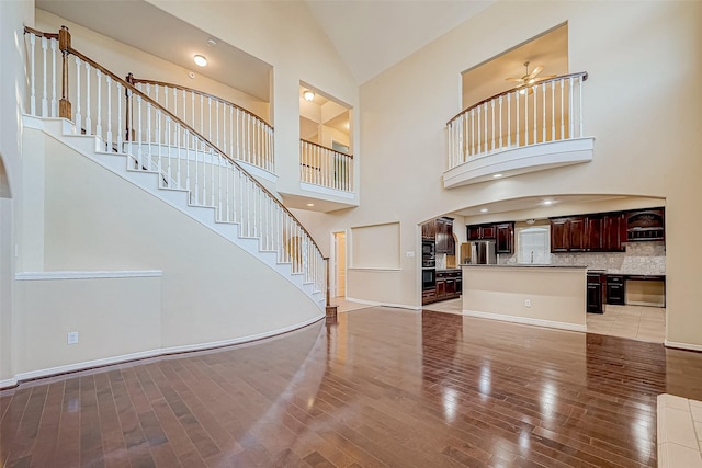 entryway with ceiling fan, high vaulted ceiling, and light wood-type flooring