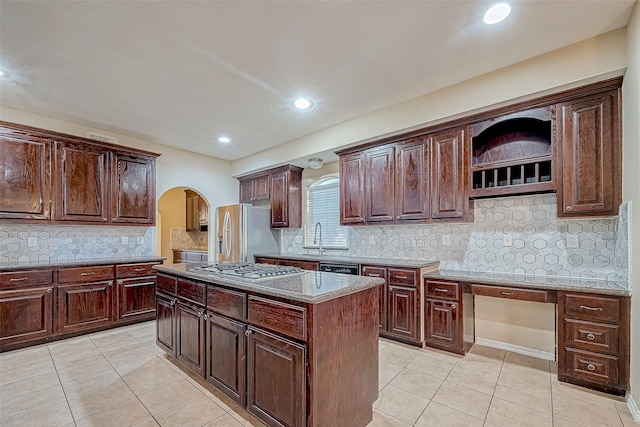 kitchen featuring appliances with stainless steel finishes, backsplash, a kitchen island, and light tile patterned flooring