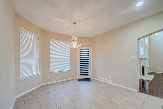 spare room with plenty of natural light, light tile patterned flooring, and a chandelier