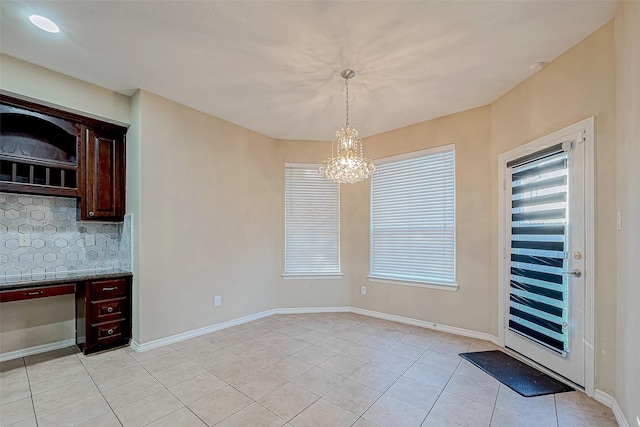 unfurnished dining area with light tile patterned floors and an inviting chandelier