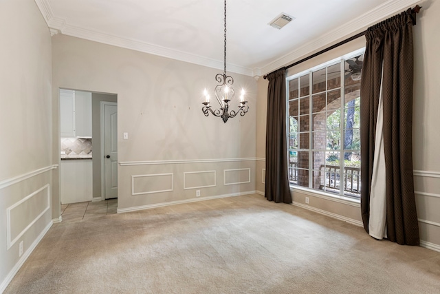 carpeted spare room with ornamental molding and an inviting chandelier