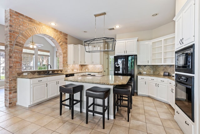 kitchen with black appliances, ceiling fan, a kitchen island, and white cabinets