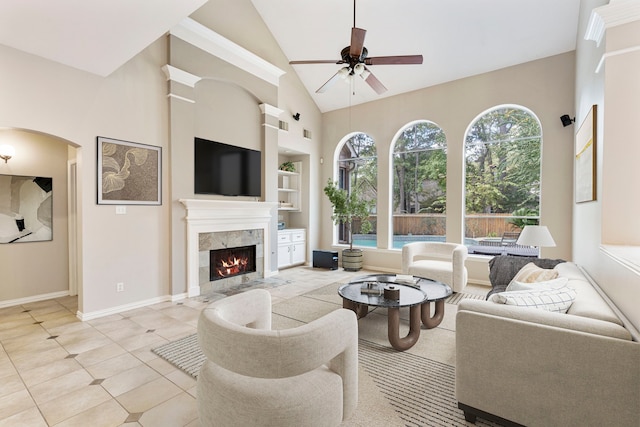 tiled living room with a tile fireplace, high vaulted ceiling, ceiling fan, and built in features