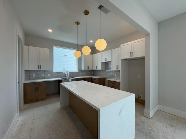 kitchen featuring white cabinets, pendant lighting, tasteful backsplash, and a kitchen island