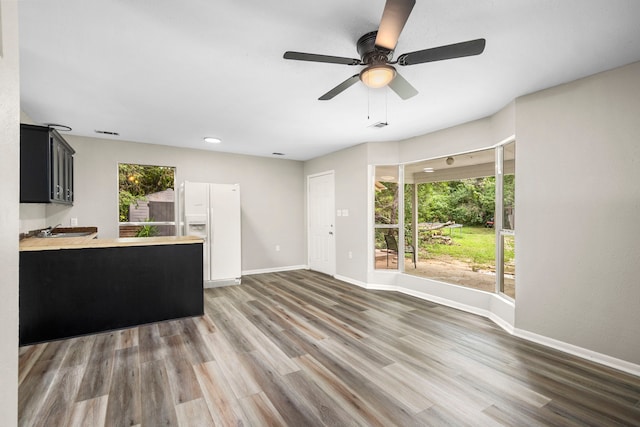 unfurnished living room with dark hardwood / wood-style flooring and ceiling fan