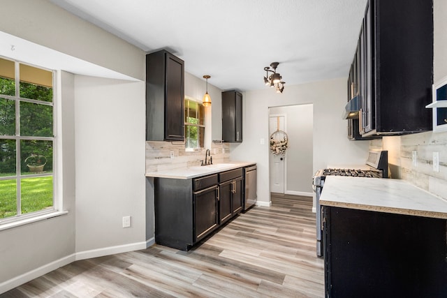 kitchen featuring stainless steel dishwasher, backsplash, pendant lighting, electric stove, and light wood-type flooring