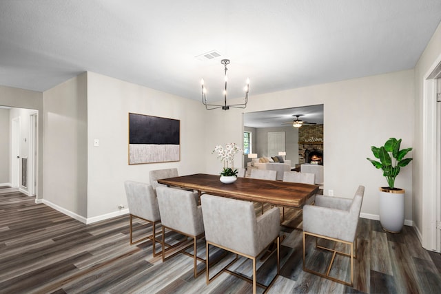 dining area featuring a fireplace, a textured ceiling, ceiling fan with notable chandelier, and dark hardwood / wood-style floors