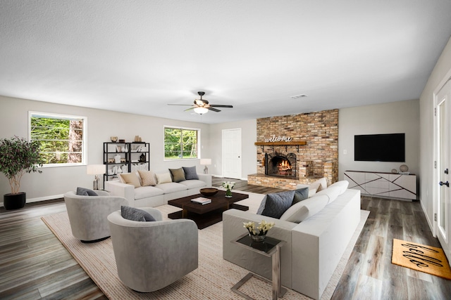 living room featuring a large fireplace, hardwood / wood-style flooring, and ceiling fan