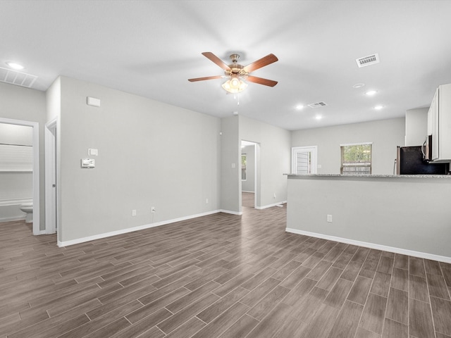 unfurnished living room featuring ceiling fan and dark hardwood / wood-style flooring