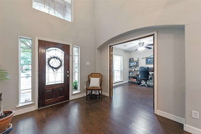 entryway with ceiling fan, dark hardwood / wood-style flooring, and a towering ceiling