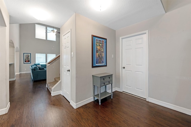 hall featuring a textured ceiling, dark hardwood / wood-style flooring, and lofted ceiling