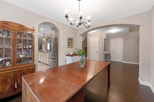 dining area with dark hardwood / wood-style floors and an inviting chandelier