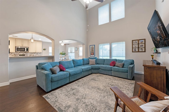 living room featuring ceiling fan, dark wood-type flooring, and a high ceiling