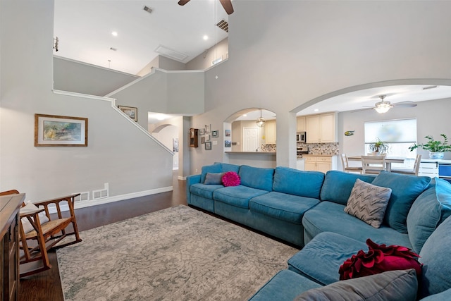 living room featuring ceiling fan, dark hardwood / wood-style floors, and a high ceiling