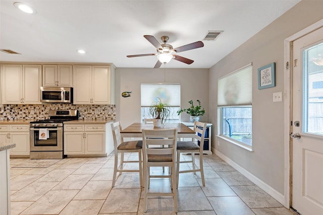 kitchen with decorative backsplash, appliances with stainless steel finishes, cream cabinetry, and ceiling fan