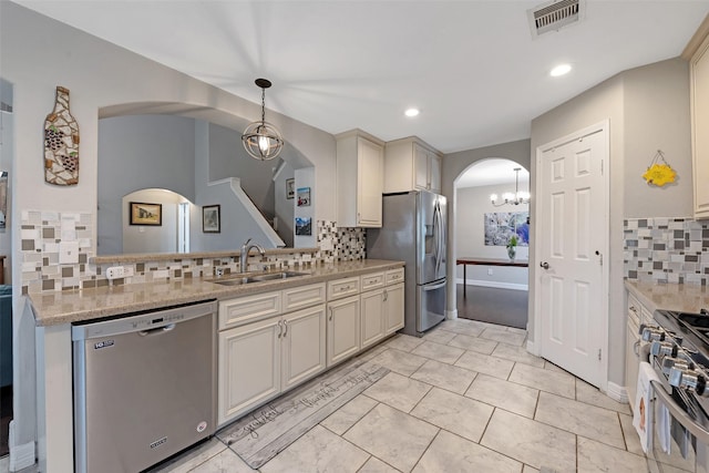 kitchen featuring hanging light fixtures, backsplash, sink, and stainless steel appliances