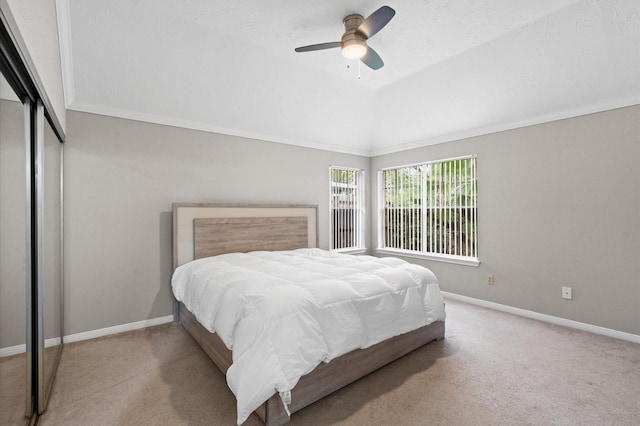 carpeted bedroom featuring ceiling fan, a closet, crown molding, and vaulted ceiling