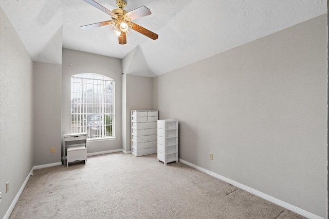 unfurnished bedroom featuring a textured ceiling, ceiling fan, light colored carpet, and vaulted ceiling