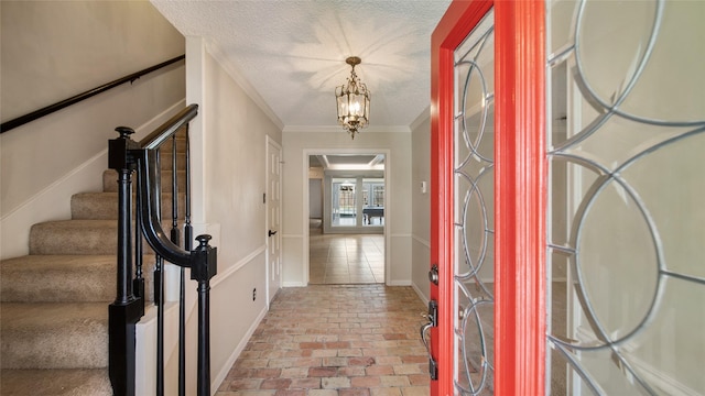 entryway featuring a chandelier, a textured ceiling, stacked washer / dryer, and crown molding