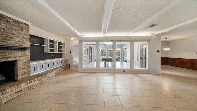 unfurnished living room featuring wood walls, light tile patterned floors, a textured ceiling, and a brick fireplace