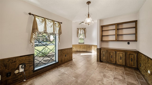 entrance foyer featuring a textured ceiling, a notable chandelier, and wood walls