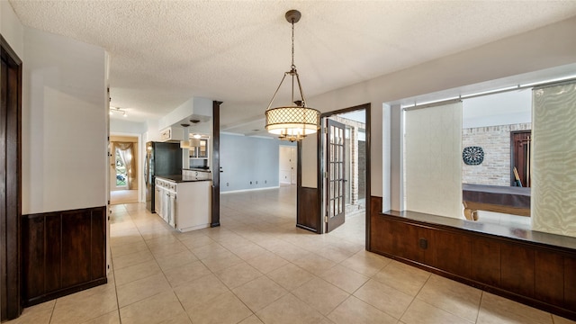 kitchen with light tile patterned floors, a textured ceiling, black fridge, and hanging light fixtures