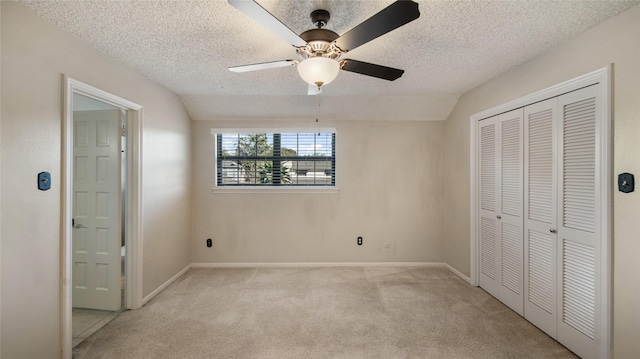 unfurnished bedroom featuring ceiling fan, light colored carpet, a textured ceiling, lofted ceiling, and a closet