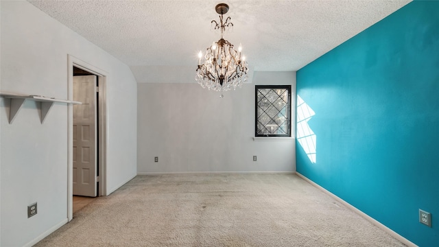 empty room featuring light colored carpet, a textured ceiling, and a chandelier