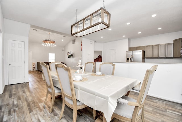 dining space with wood-type flooring and vaulted ceiling