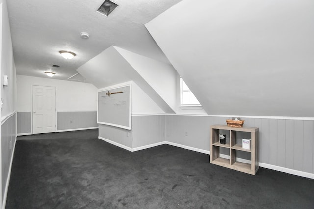 bonus room featuring dark colored carpet, a textured ceiling, and vaulted ceiling