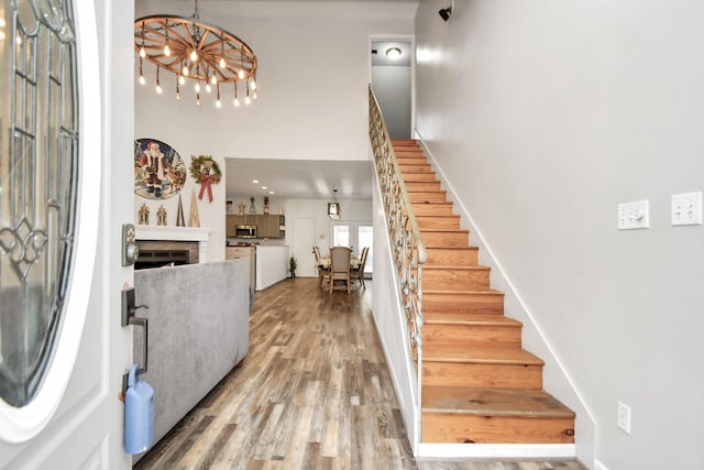 foyer entrance with a fireplace, a chandelier, and hardwood / wood-style flooring