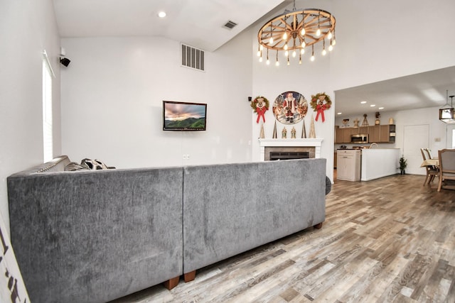 living room with hardwood / wood-style flooring, high vaulted ceiling, and a chandelier