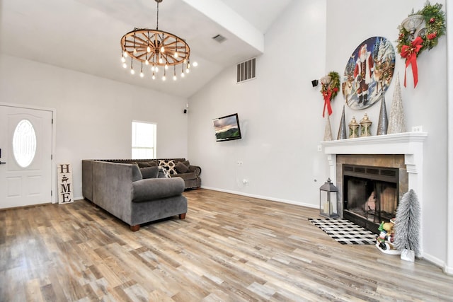 living room with a fireplace, hardwood / wood-style floors, high vaulted ceiling, and a notable chandelier