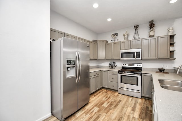 kitchen with light wood-type flooring, stainless steel appliances, gray cabinets, and sink