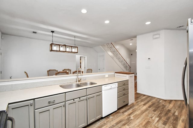 kitchen featuring pendant lighting, hardwood / wood-style floors, white dishwasher, sink, and gray cabinets