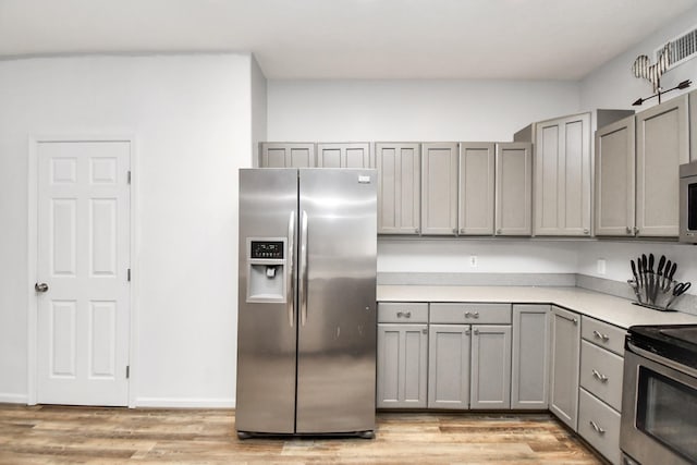 kitchen with gray cabinetry, light hardwood / wood-style flooring, and stainless steel appliances