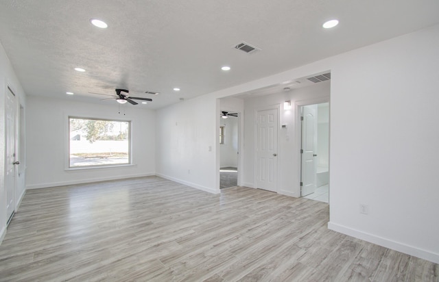 spare room with a textured ceiling, light wood-type flooring, and ceiling fan