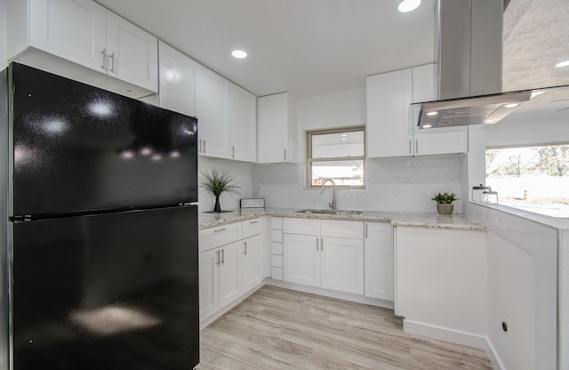 kitchen with a healthy amount of sunlight, black fridge, and white cabinetry