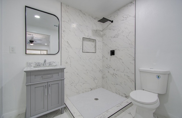 bathroom featuring a tile shower, vanity, toilet, and ceiling fan