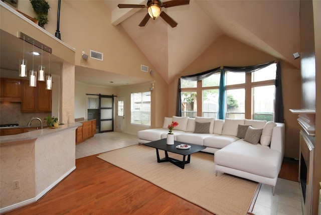 living room featuring a barn door, ceiling fan, high vaulted ceiling, and light wood-type flooring