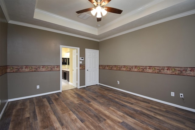 empty room featuring ceiling fan, a raised ceiling, crown molding, and dark wood-type flooring