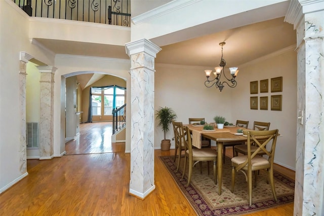 dining space with ornate columns, ornamental molding, a chandelier, and hardwood / wood-style flooring