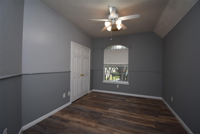 empty room featuring dark hardwood / wood-style floors, vaulted ceiling, and ceiling fan