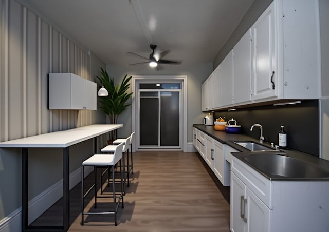 kitchen with white cabinets, ceiling fan, wood-type flooring, and sink