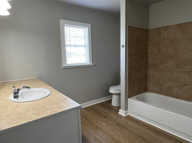 full bathroom with tiled shower / bath, vanity, wood-type flooring, and toilet