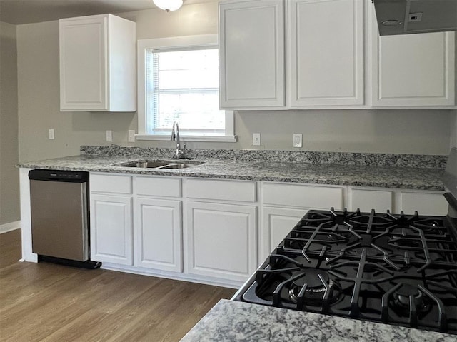 kitchen with sink, stainless steel dishwasher, hardwood / wood-style flooring, light stone counters, and white cabinetry